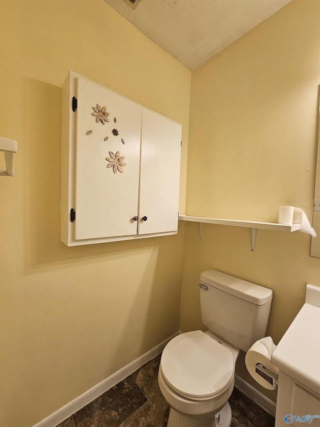 bathroom with toilet, baseboards, and a textured ceiling