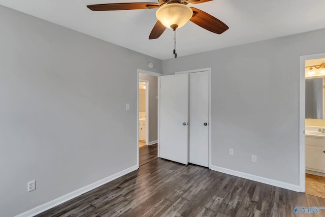 unfurnished bedroom featuring connected bathroom, ceiling fan, baseboards, wood finished floors, and a closet