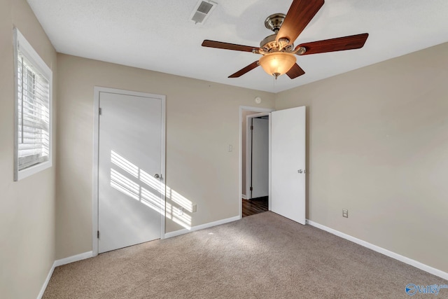 unfurnished bedroom featuring visible vents, ceiling fan, baseboards, and carpet