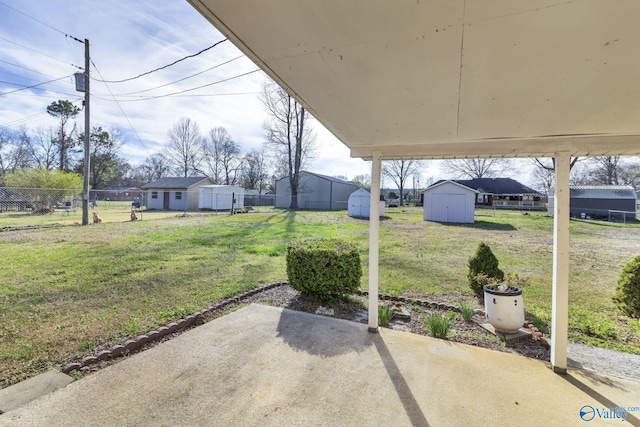 view of yard featuring a storage shed, fence, an outdoor structure, and a patio