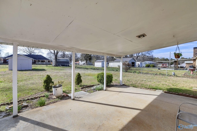 view of patio / terrace featuring an outbuilding, a storage unit, fence, and a carport