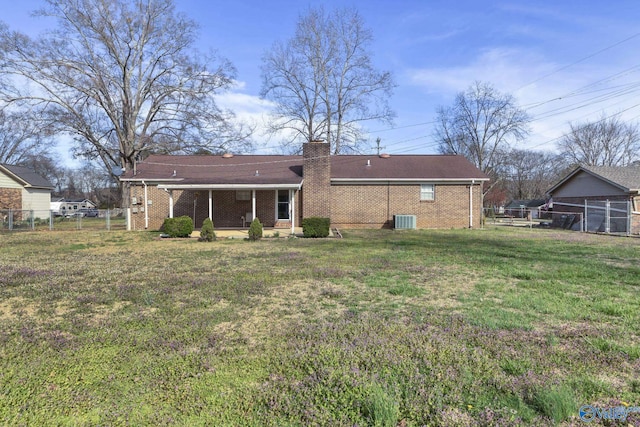 rear view of house featuring cooling unit, fence, a chimney, a lawn, and brick siding
