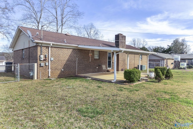 rear view of property featuring a patio, fence, a yard, brick siding, and a chimney