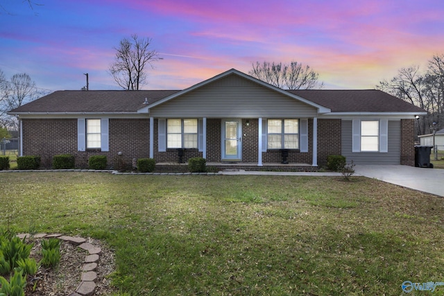 ranch-style home with brick siding, roof with shingles, and a front lawn