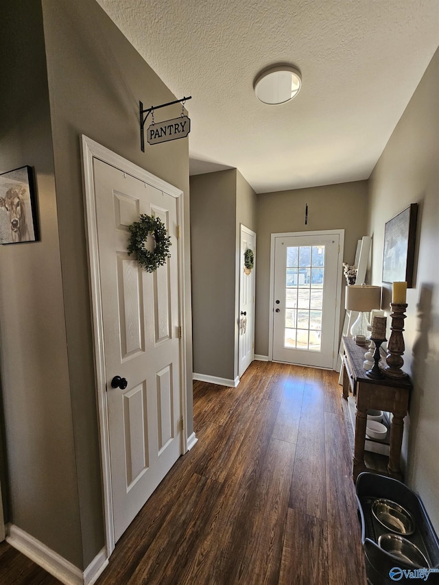 entryway featuring dark wood-style flooring, baseboards, and a textured ceiling