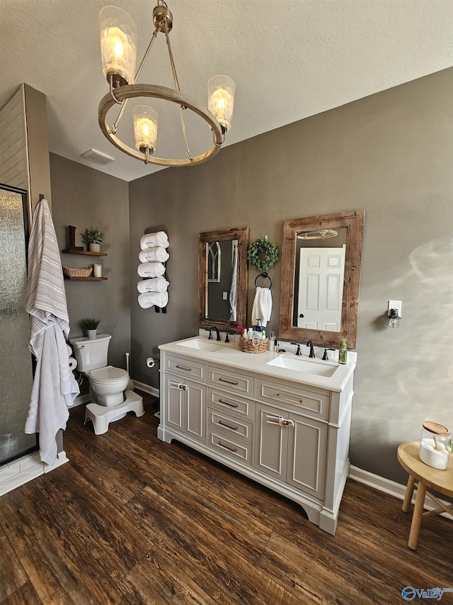 full bath with a chandelier, toilet, wood finished floors, baseboards, and a textured ceiling