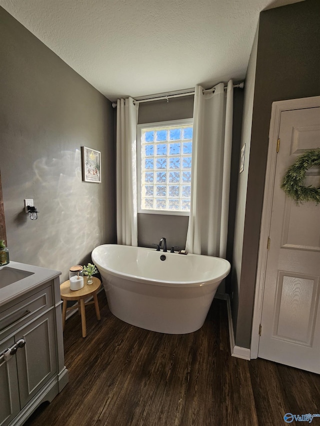 full bathroom featuring wood finished floors, a freestanding bath, a textured ceiling, and vanity