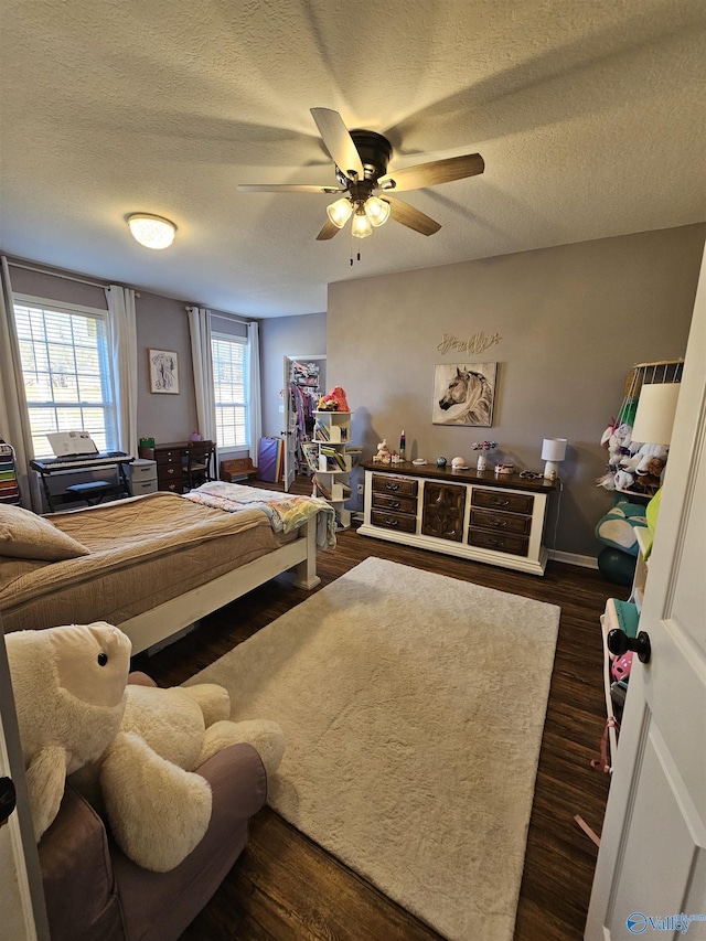 bedroom with dark wood finished floors, a textured ceiling, ceiling fan, and baseboards