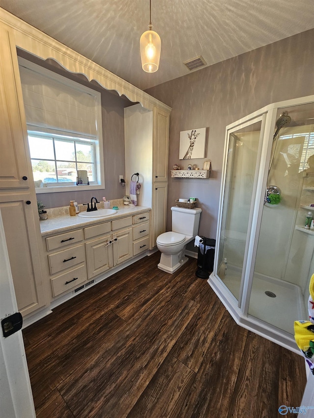 bathroom with wood finished floors, a shower stall, toilet, and vanity