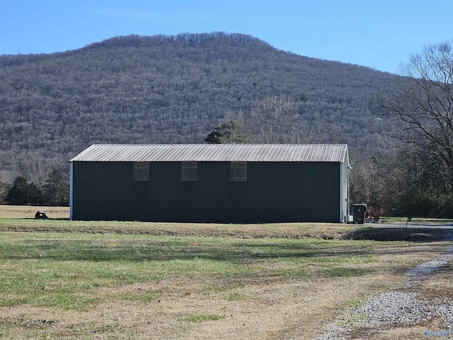 view of pole building with a mountain view, a forest view, and a lawn