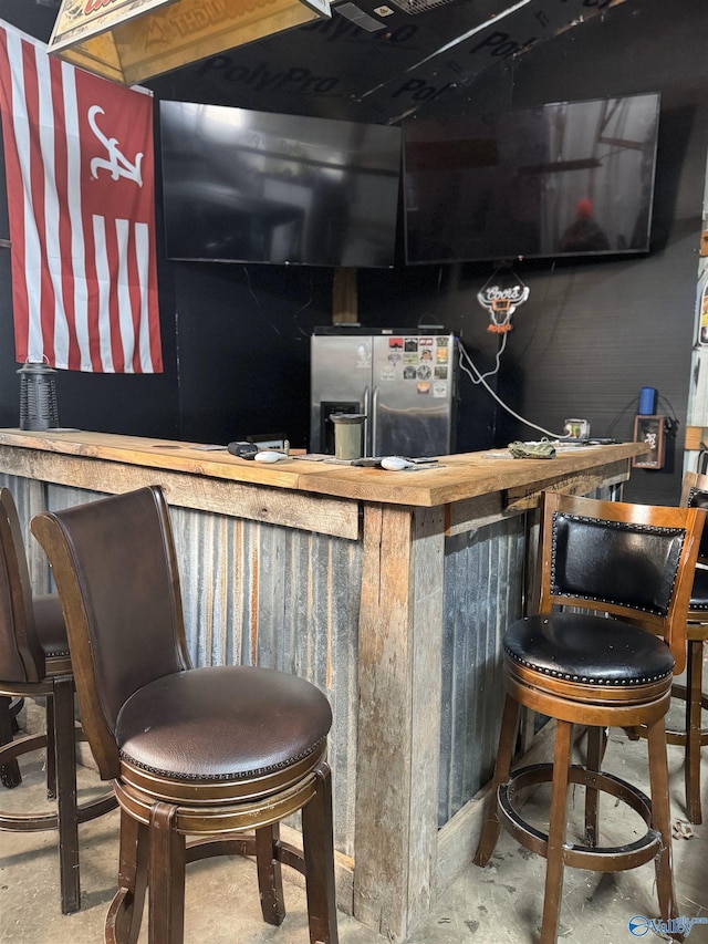 indoor dry bar with stainless steel fridge with ice dispenser and unfinished concrete flooring
