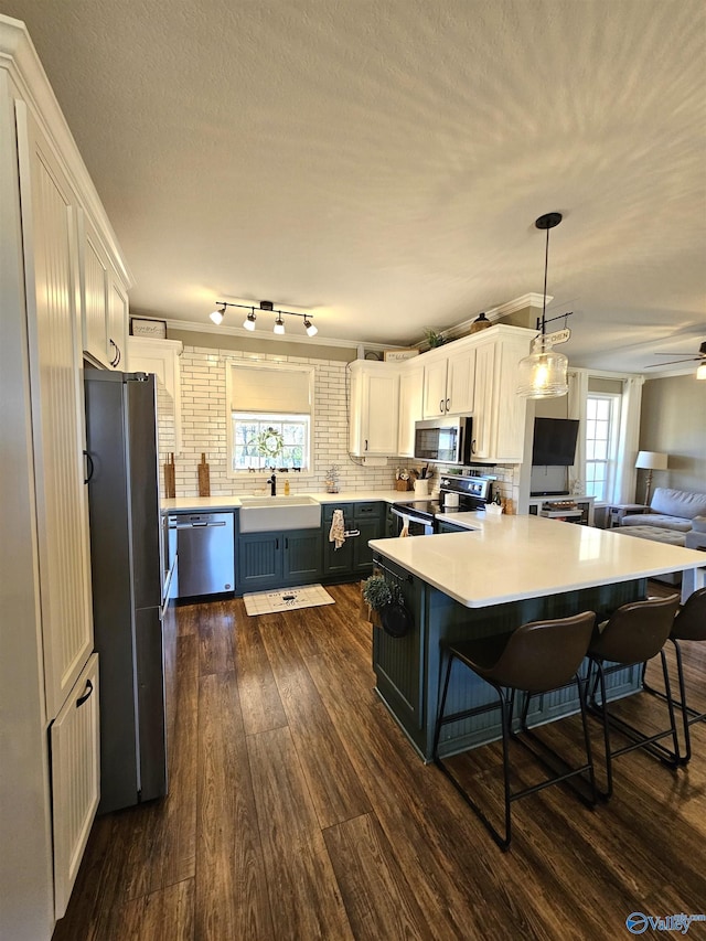 kitchen featuring appliances with stainless steel finishes, white cabinetry, and a kitchen breakfast bar