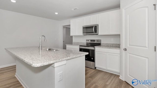 kitchen featuring appliances with stainless steel finishes, a kitchen island with sink, sink, light hardwood / wood-style flooring, and white cabinetry