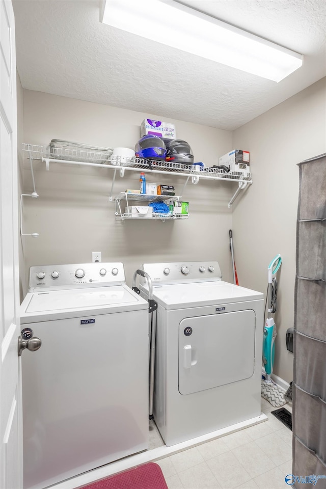 laundry room featuring washer and dryer and a textured ceiling