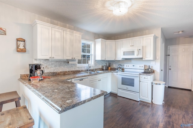 kitchen featuring sink, white cabinets, dark hardwood / wood-style flooring, kitchen peninsula, and white appliances