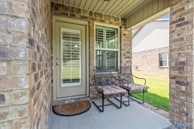 doorway to property featuring brick siding, a porch, and stone siding