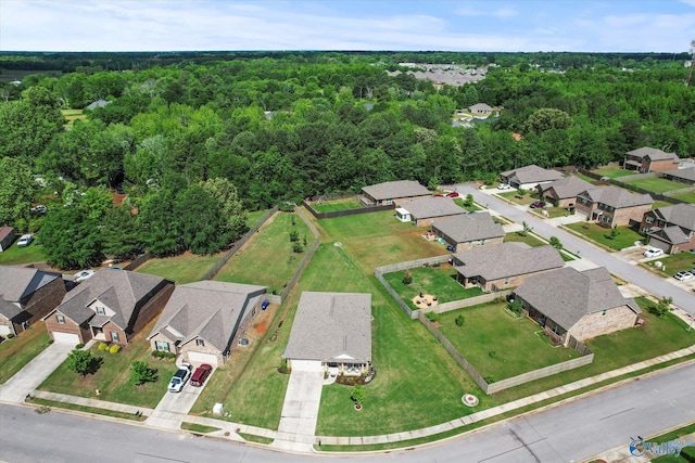 aerial view of property and surrounding area featuring a heavily wooded area and nearby suburban area