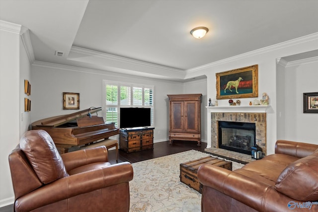 living area with dark wood-style flooring, a fireplace with raised hearth, ornamental molding, baseboards, and a tray ceiling