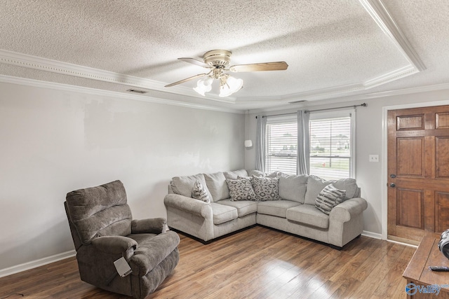 living room featuring wood-type flooring, ceiling fan, crown molding, a raised ceiling, and a textured ceiling