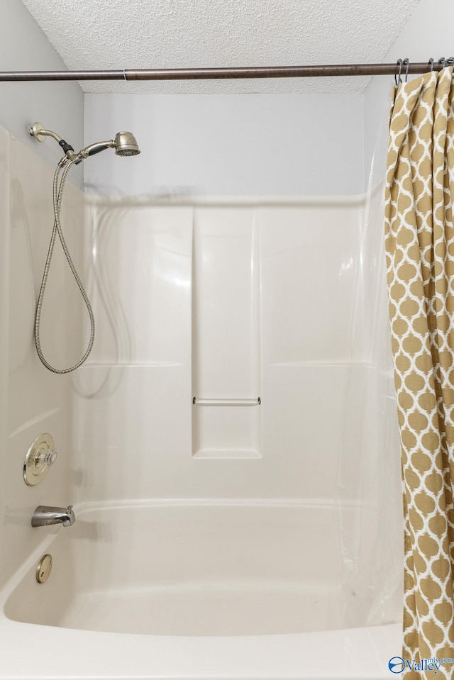 bathroom with a textured ceiling and shower / bathtub combination with curtain