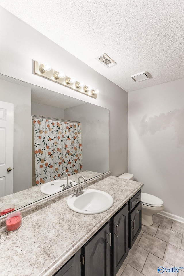 bathroom with tile patterned floors, toilet, vanity, and a textured ceiling