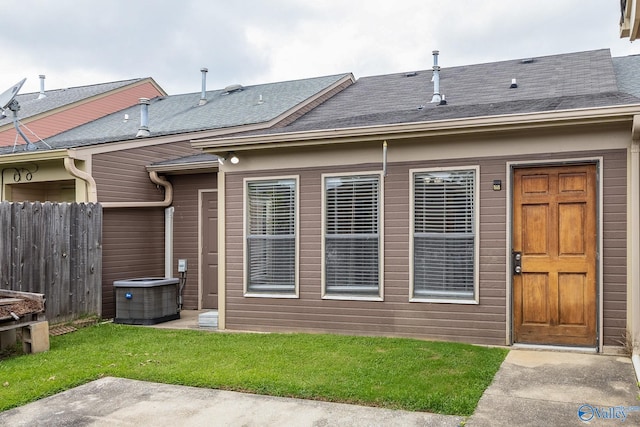 rear view of house with central air condition unit and a yard