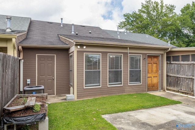 back of property with central AC and a lawn