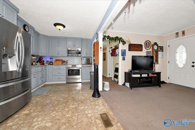 kitchen featuring a textured ceiling, appliances with stainless steel finishes, gray cabinetry, and tasteful backsplash