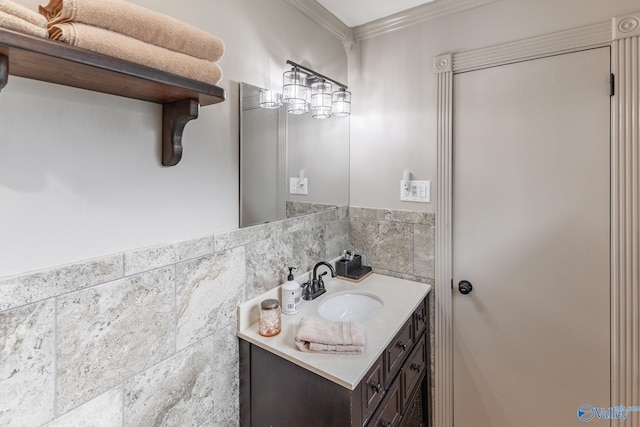 bathroom featuring crown molding, wainscoting, vanity, and tile walls