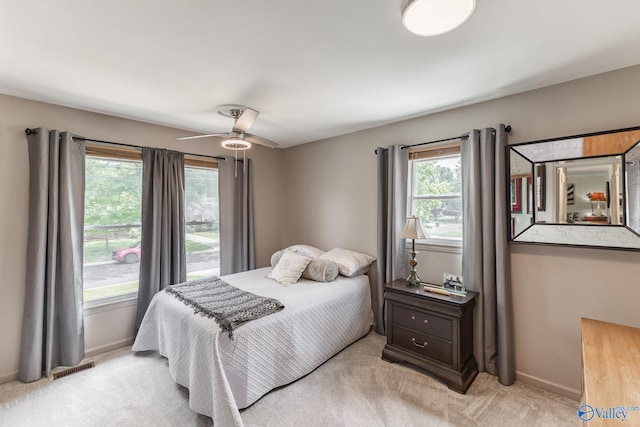bedroom featuring baseboards, a ceiling fan, visible vents, and light carpet