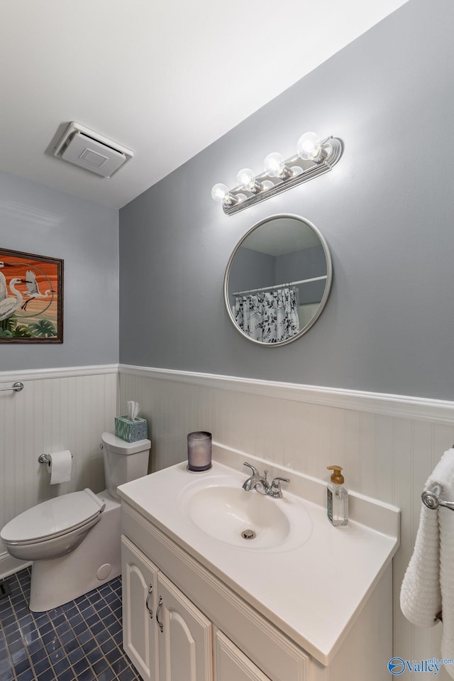 full bath with tile patterned flooring, wainscoting, toilet, and visible vents