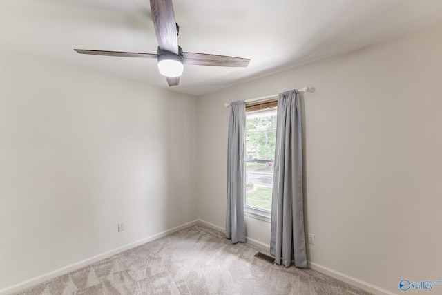 spare room with light colored carpet, a ceiling fan, baseboards, and visible vents