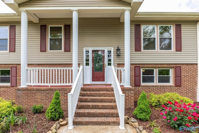 entrance to property with covered porch and brick siding