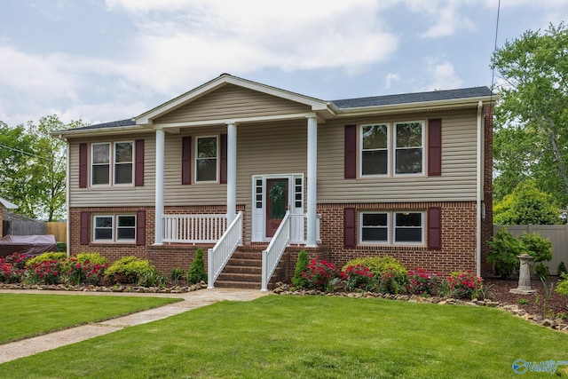 raised ranch with covered porch, brick siding, and a front lawn