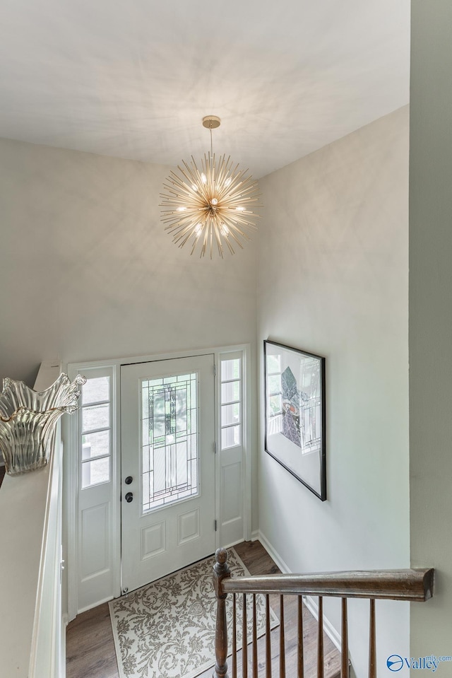 foyer entrance with baseboards, a wealth of natural light, wood finished floors, and a chandelier