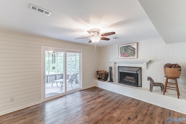 living room with ceiling fan, a brick fireplace, wood finished floors, and visible vents