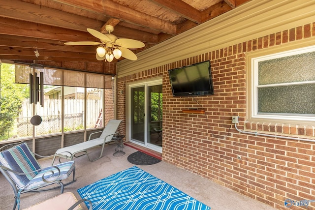 sunroom with ceiling fan and beam ceiling