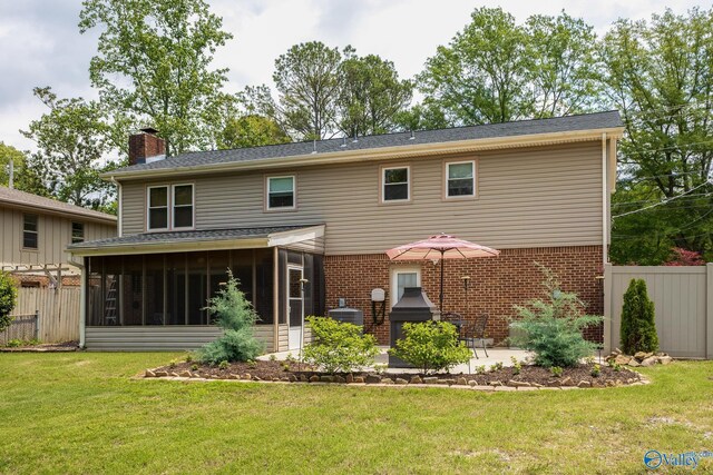 back of house featuring fence, a chimney, brick siding, a sunroom, and a lawn