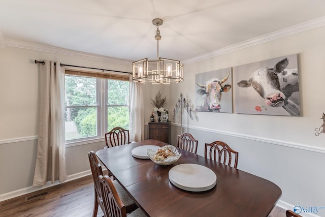 dining space with an inviting chandelier, ornamental molding, wood finished floors, and visible vents