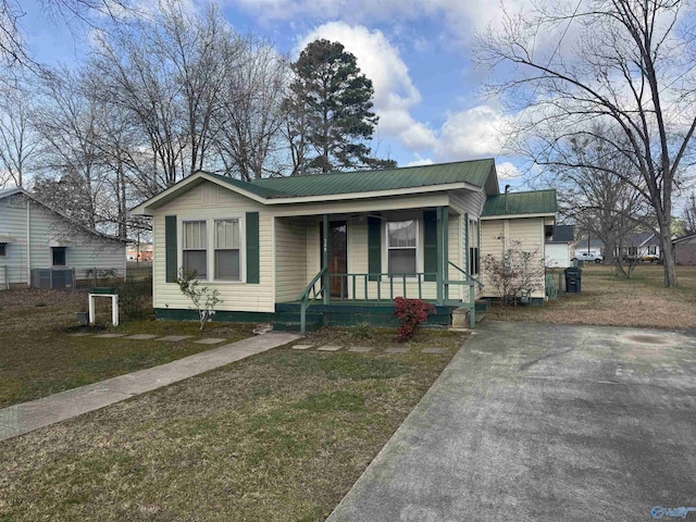 bungalow-style house with a front lawn, covered porch, and metal roof