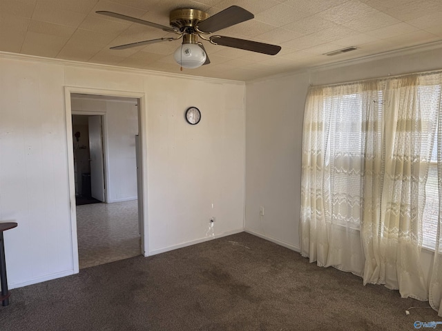 empty room with ceiling fan, visible vents, ornamental molding, and carpet flooring