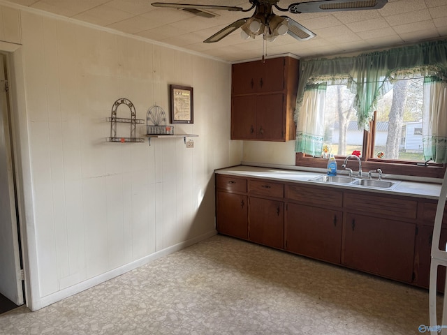 kitchen with ceiling fan, light floors, light countertops, ornamental molding, and a sink