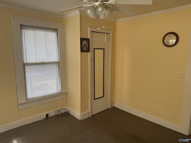 empty room featuring a ceiling fan, dark colored carpet, and ornamental molding