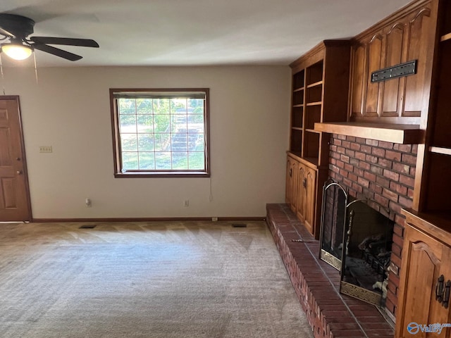 unfurnished living room with a brick fireplace, carpet floors, and ceiling fan