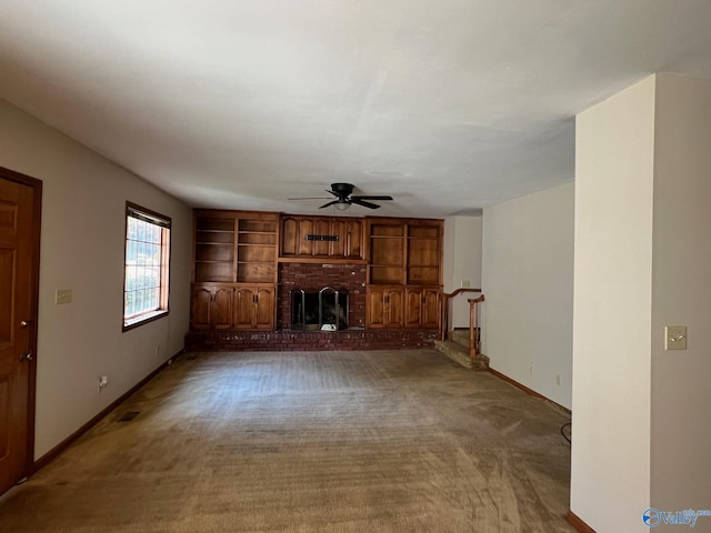 unfurnished living room featuring a brick fireplace, carpet floors, and ceiling fan