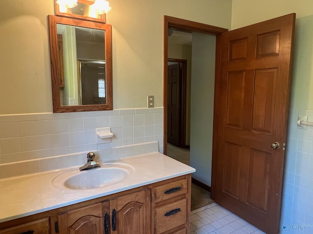 bathroom with tile walls, vanity, a shower with door, and tile patterned flooring