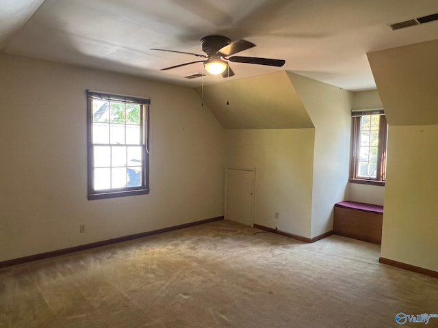 bonus room featuring ceiling fan, a healthy amount of sunlight, lofted ceiling, and light carpet