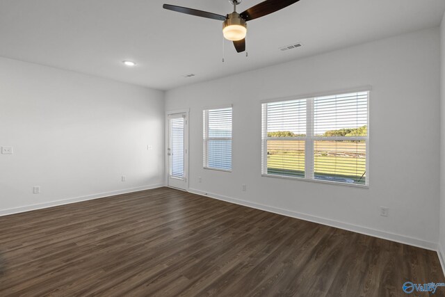 empty room with a ceiling fan, visible vents, baseboards, and dark wood-style flooring