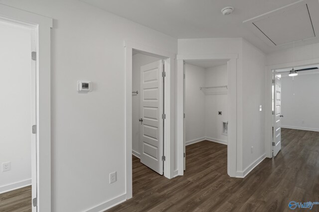 corridor featuring baseboards, attic access, and dark wood finished floors