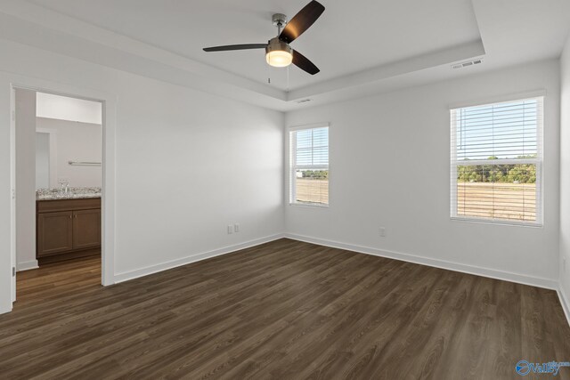 unfurnished bedroom with dark wood finished floors, visible vents, and a raised ceiling